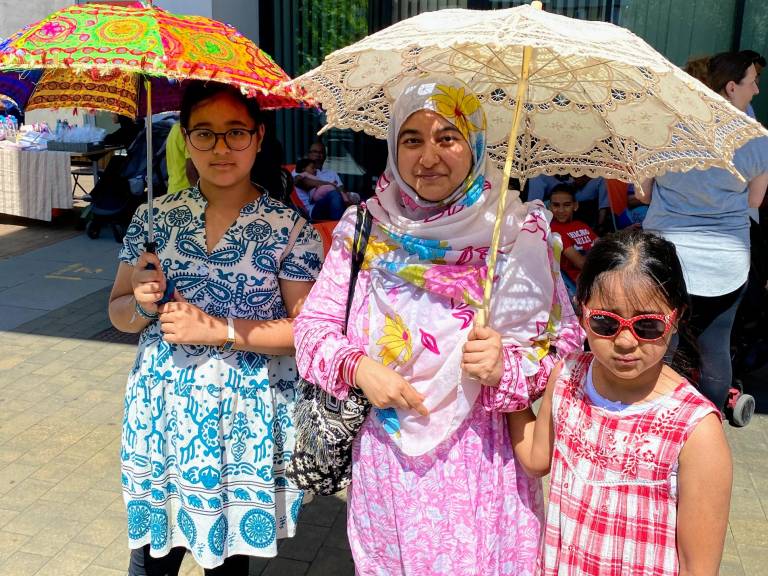 A mother and her two young daughters attend the St Paul's Way Summer of Wellbeing Festival, wearing bright patterned clothes and parasols