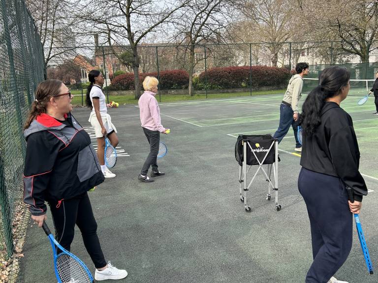 Players at Community Tennis for Health line up on one side of the net to take part in a volley drill during a session