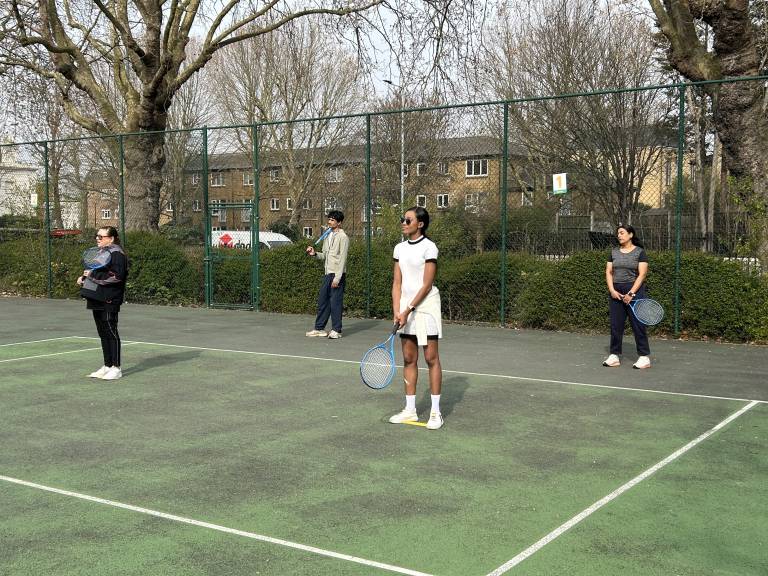 Four Community Tennis for Health players stand on one side of the court, ready to play tennis drills.