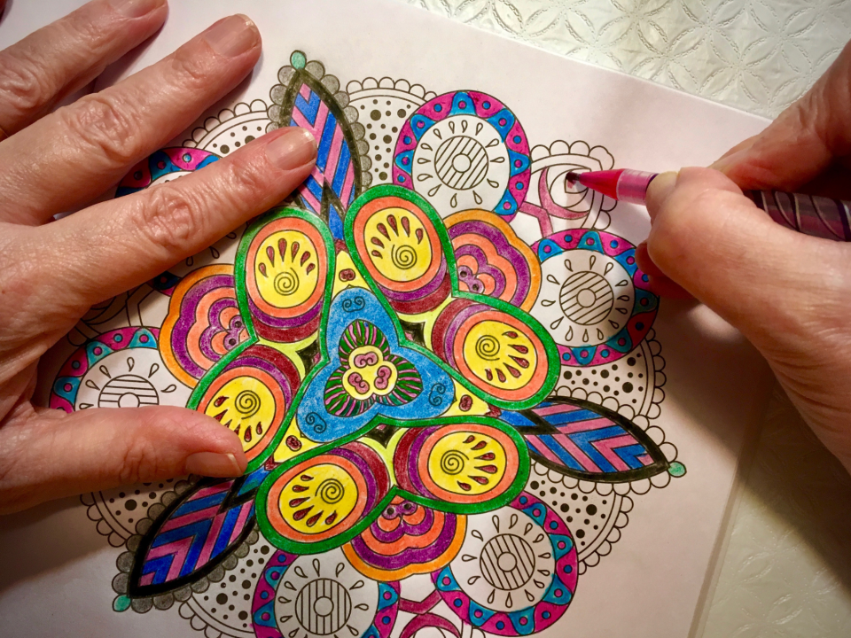 Person relaxing by colouring a mandala pattern