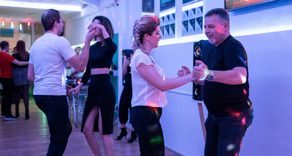 Men and women dancing salsa together in a community centre class